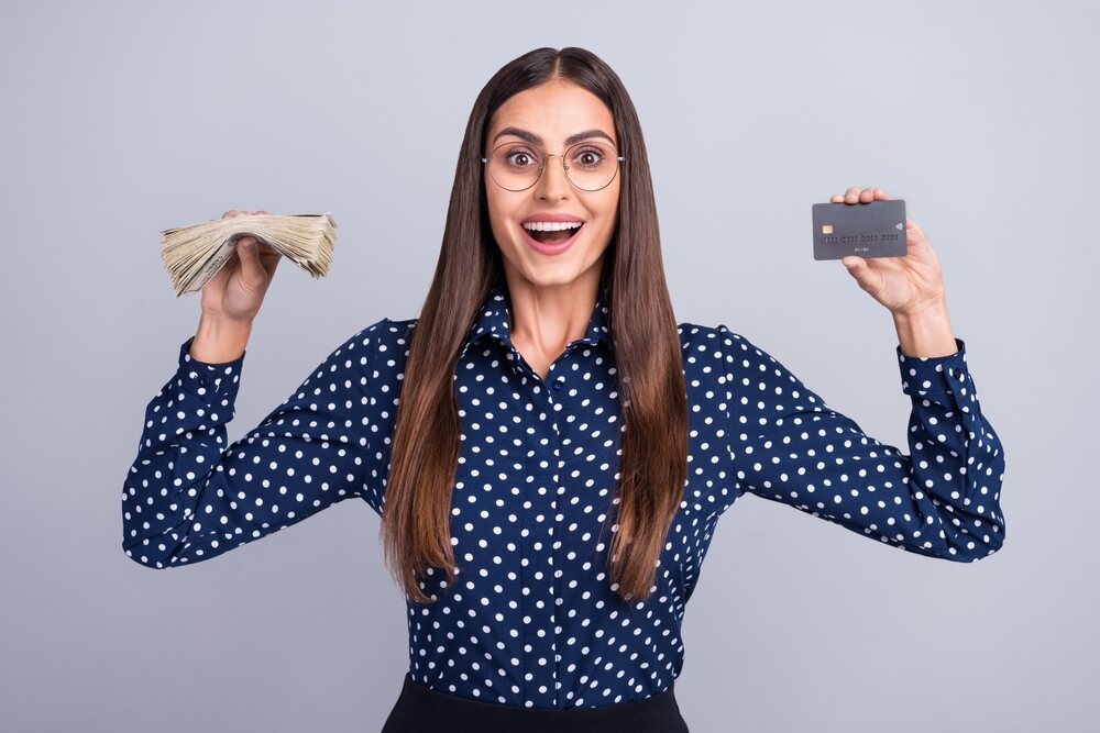 Mulher feliz segurando dinheiro e cartão